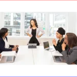 A group of people sitting at a table with laptops.